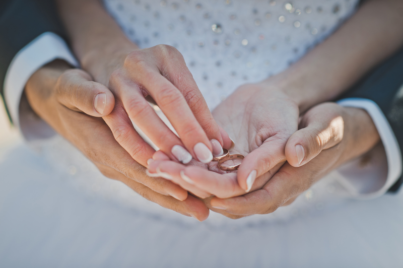 Mans and female hands hold wedding rings.